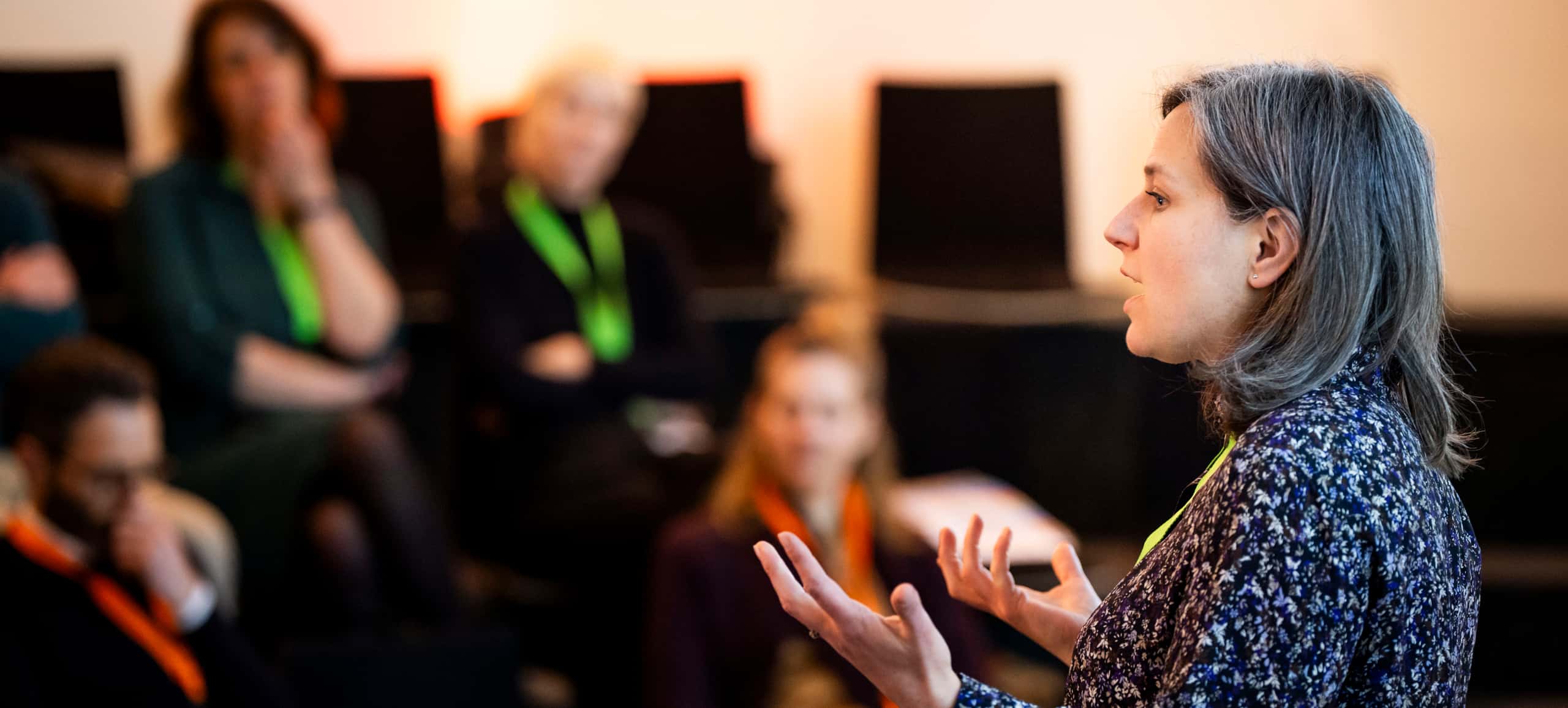Kuschminder spreekt en op de achtergrond het publiek