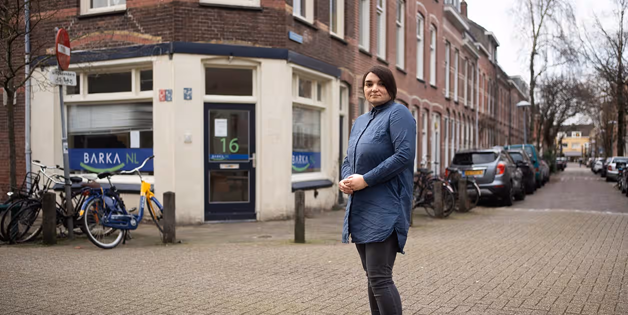 Een vrouw op straat voor het pand van Stichting Barka