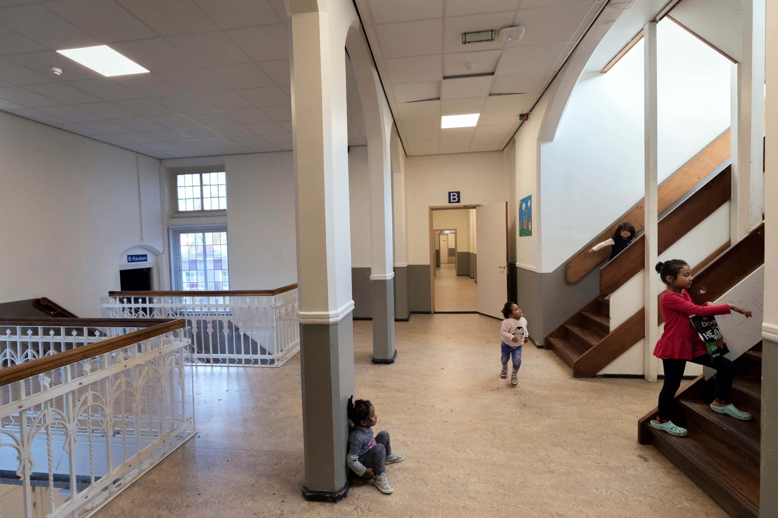 Spelende kinderen in een gang en trappenhuis.